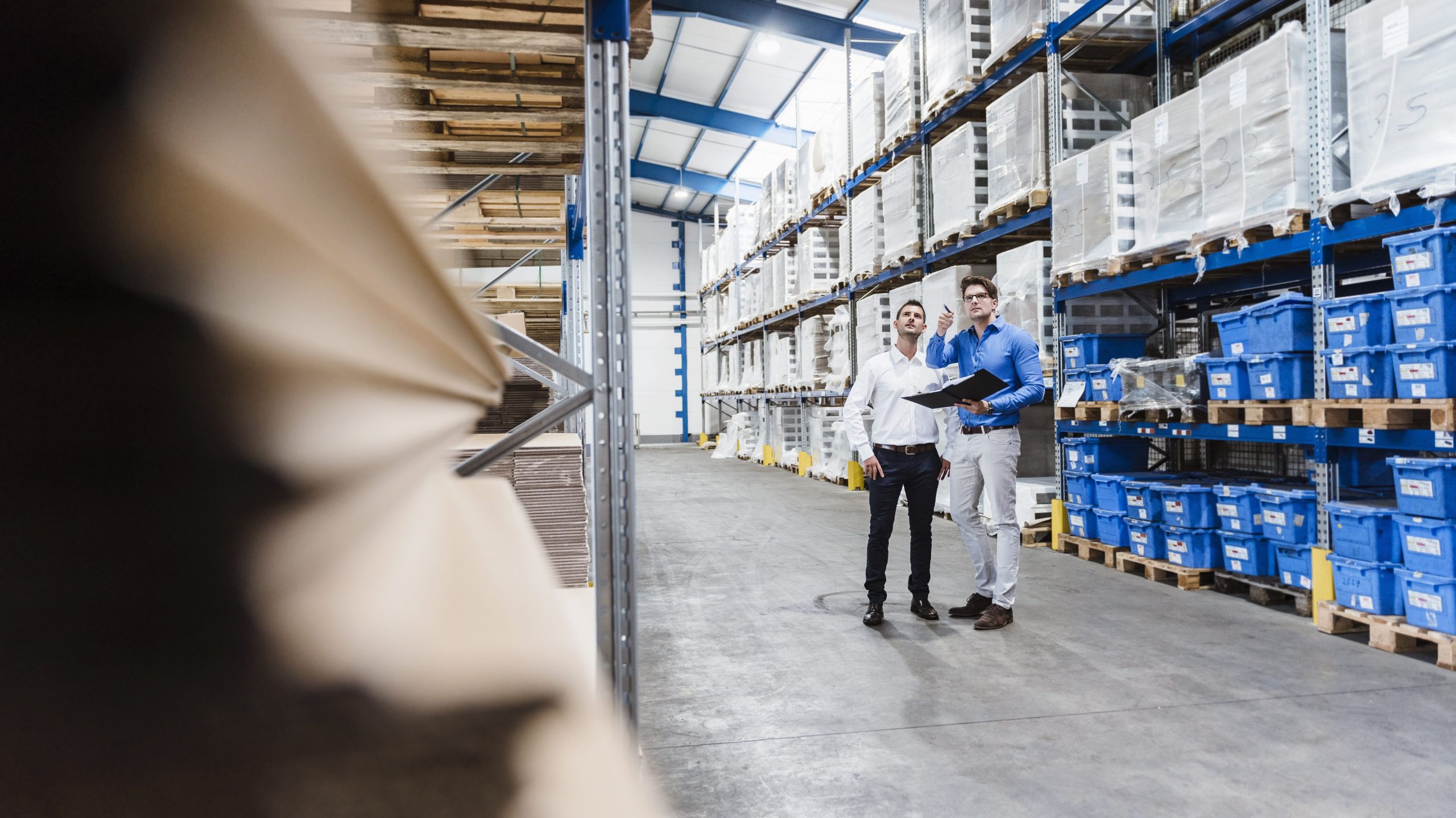 Two professionals inspecting organized shelves in a spacious warehousing and storage facility, showcasing efficient storage solutions.