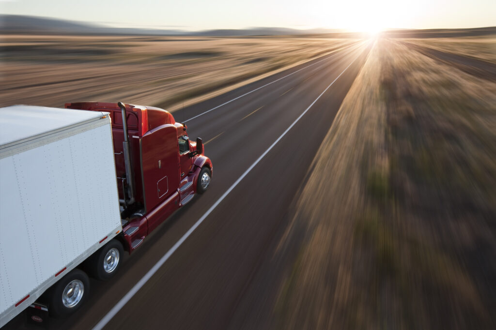 A red truck driving on an open road at sunset, representing Temperature-Controlled LTL transportation.