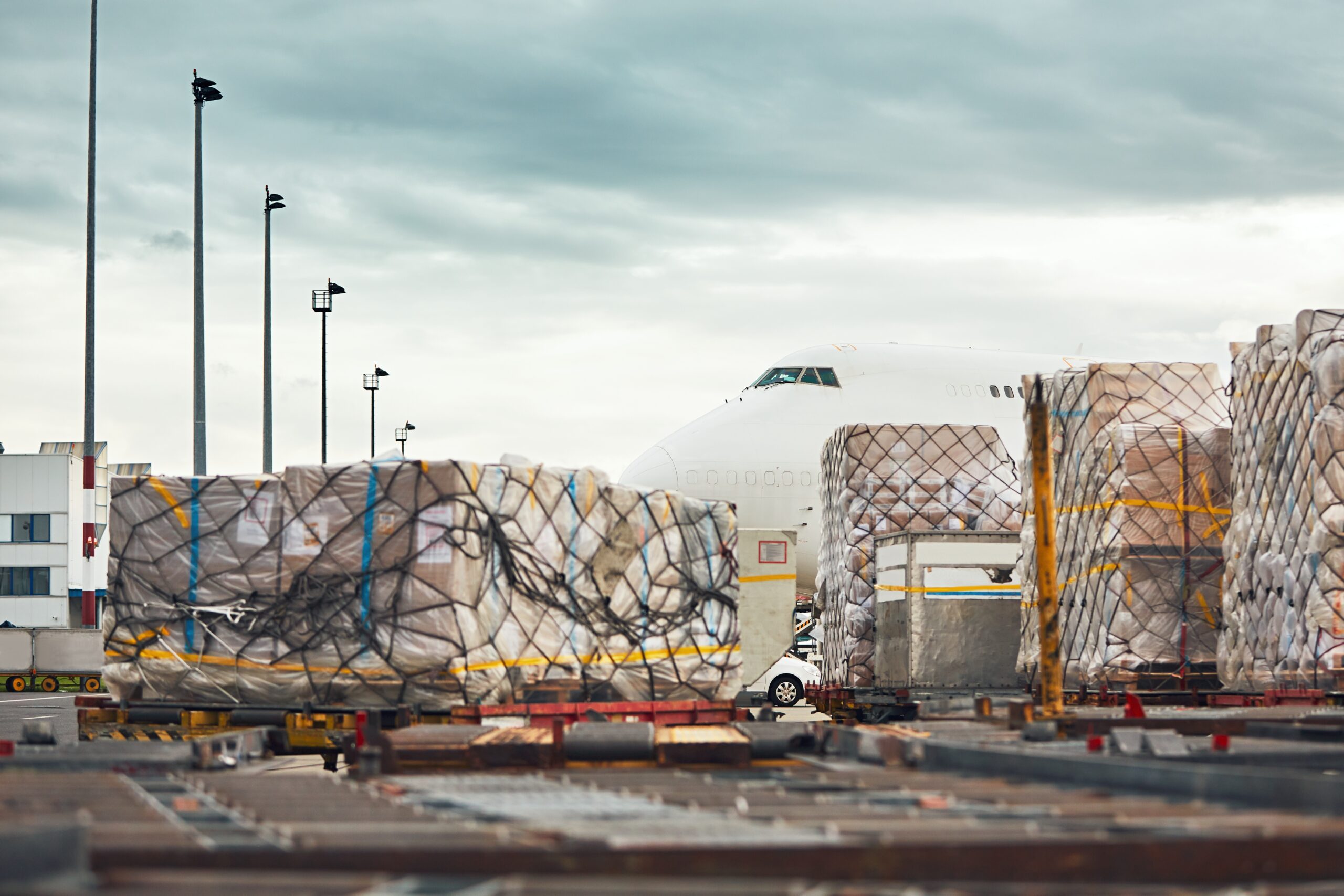 Cross Border Logistics: Cargo being loaded onto an airplane for international shipping, showing freight pallets wrapped and ready for transport at an airport.