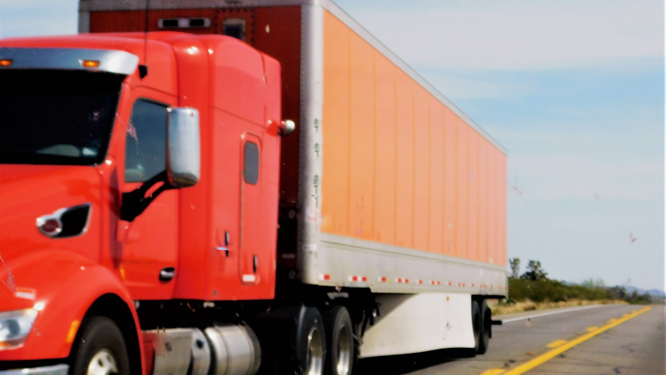 Red truck and trailer on highway representing international shipping for small businesses