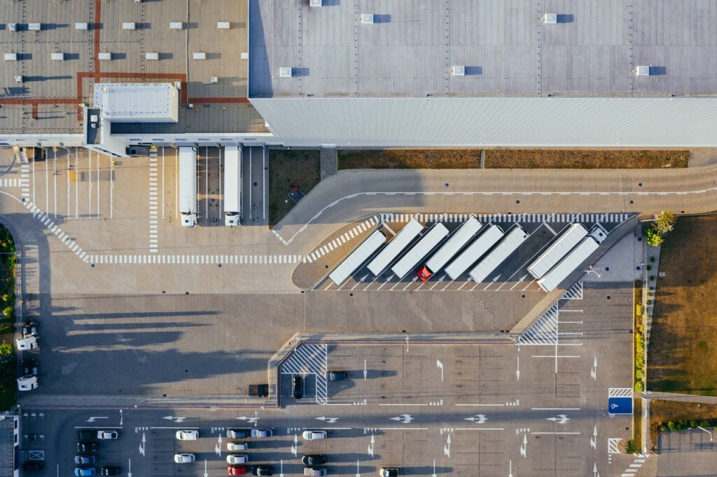 Aerial view of a trucking facility with semi-trucks parked near a warehouse and loading docks.