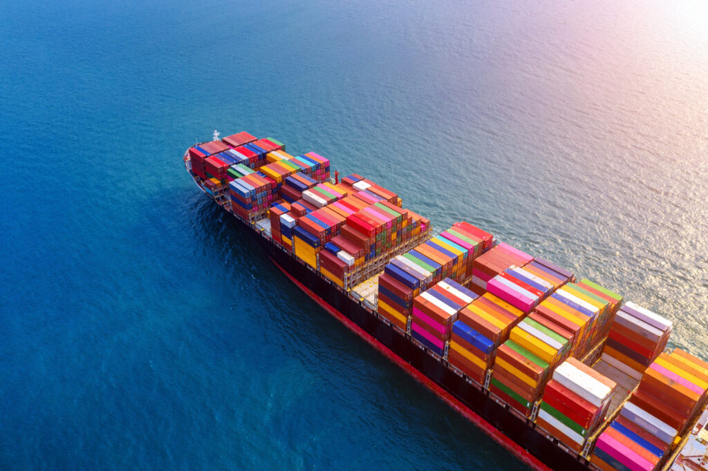 Cargo ship carrying colorful containers across the ocean, representing international logistics and broker operations.